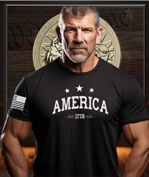 American Patriot Man wearing a black Patriot Gear USA  t-shirt with 'AMERICA 1776' text in front of an American flag and emblem.