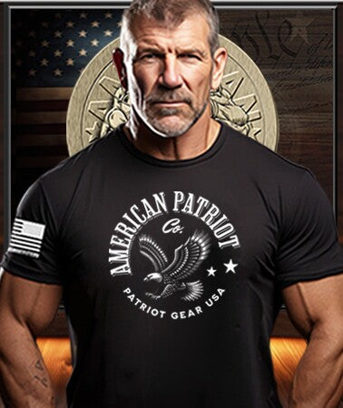 Patriot Gear USA American Man wearing a black Patriot Gear USA  t-shirt with 'American Patriot Company' text in front of an American flag and American Outfitters Patriot Apparel Company logo.