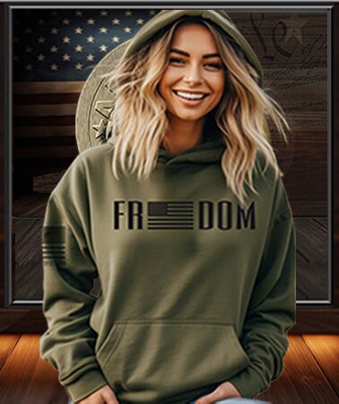 Americsn Patriot Female green hoodie with 'FREEDOM' printed on it, standing in front of an American Outfitter flag anmd patriot Apparel Back ground.